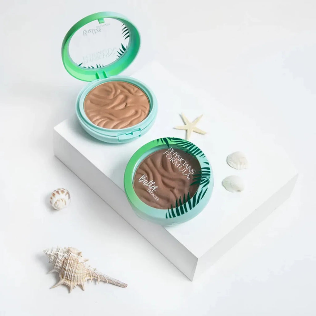 Physicians Formula Butter Bronzer compacts in tropical green packaging, displayed with seashells and starfish on white platform